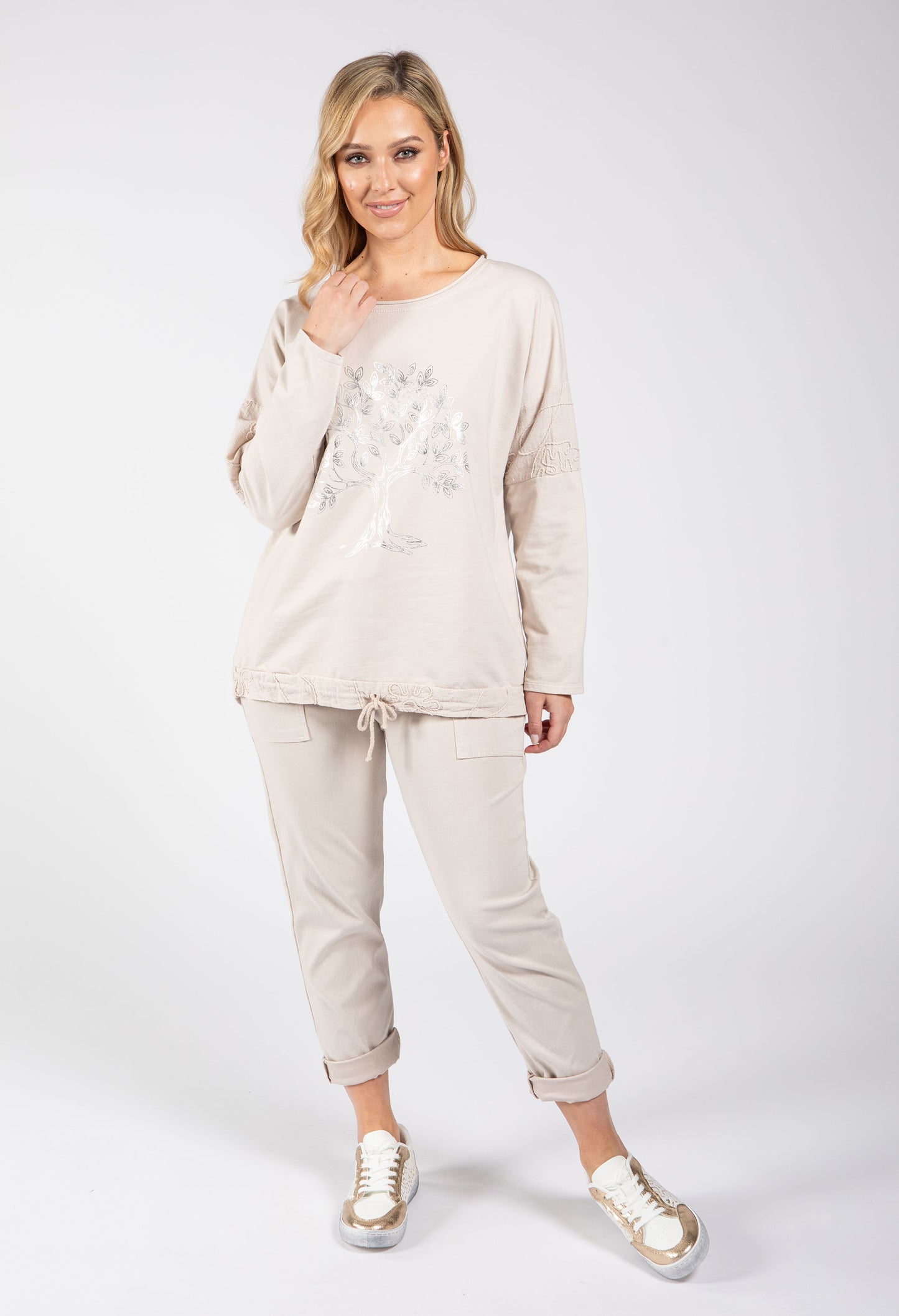 Woman wearing a beige tracksuit with a white background
