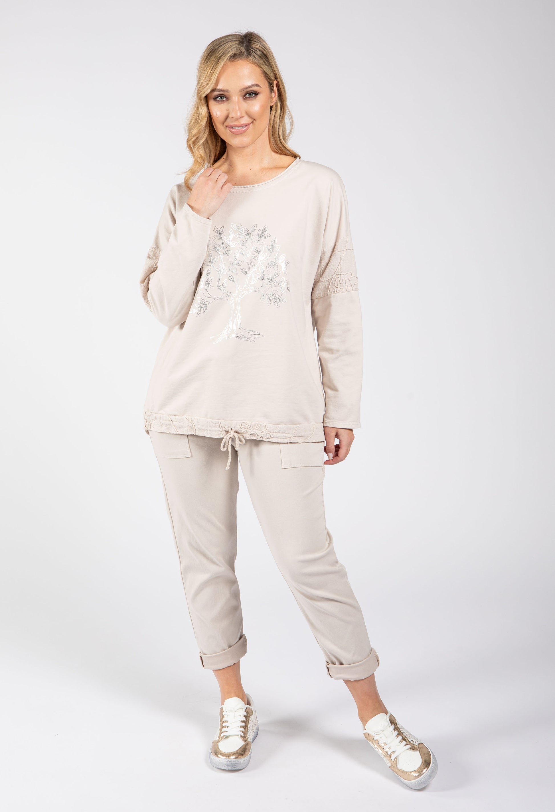 Woman wearing a beige tracksuit with a white background