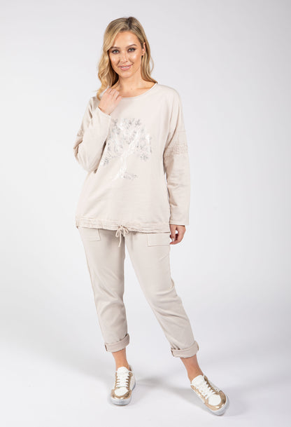 Woman wearing a beige tracksuit with a white background