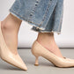 Beige high-heeled shoes worn with denim jeans on a neutral background