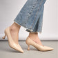 Beige high-heeled shoes worn with a denim skirt on a neutral background