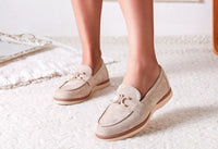 Beige loafers worn by a person on a light-colored carpet