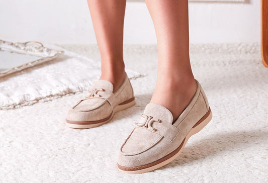 White loafers worn by a person on a light-colored floor.