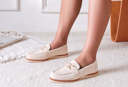 White loafers worn by a person on a light-colored floor.