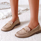 Beige loafers with gold accents worn by a person on a light background
