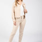 Woman wearing a beige outfit with a jacket and pants on a white background