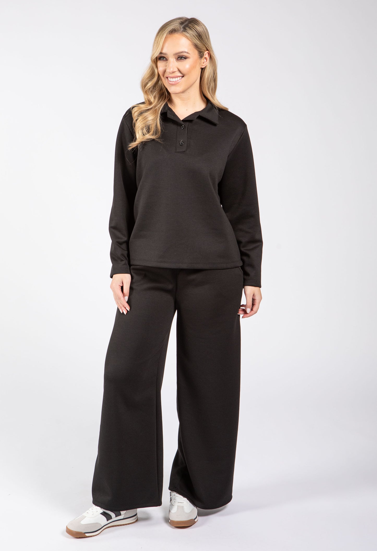 Woman wearing a black long-sleeve shirt and black pants on a white background