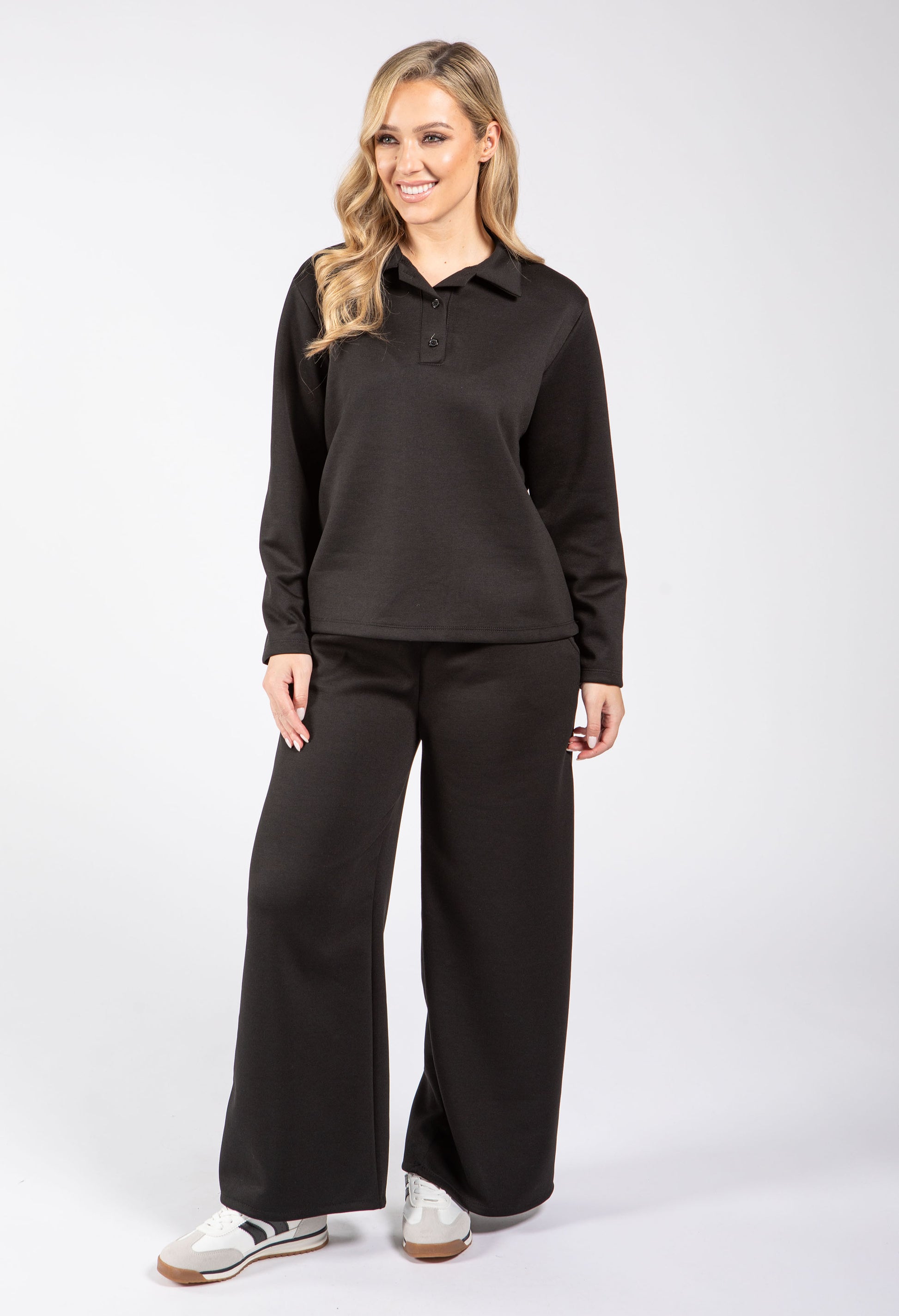 Woman wearing a black long-sleeve shirt and black pants on a white background