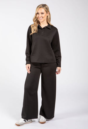 Woman wearing a black long-sleeve shirt and black pants on a white background