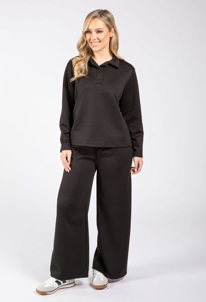 Woman wearing a black long-sleeve shirt and black pants on a white background