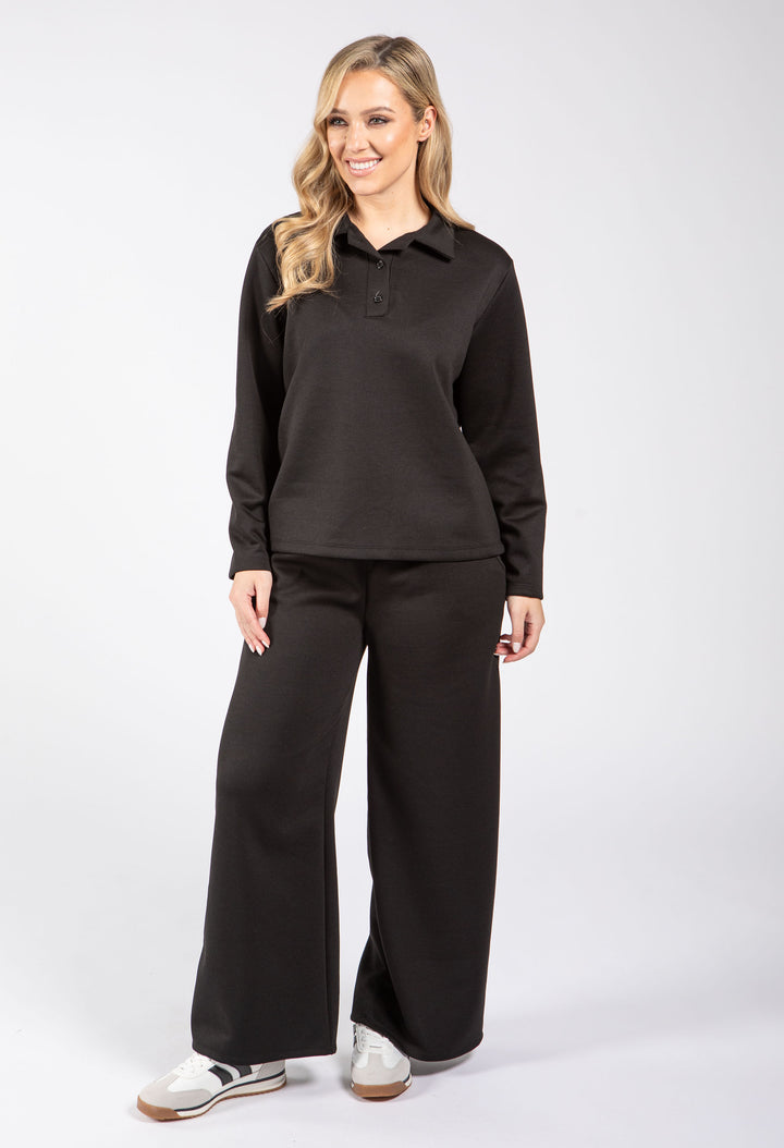 Woman wearing a black long-sleeve shirt and black pants on a white background
