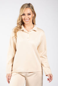 Woman wearing a beige long-sleeve shirt and pants on a white background