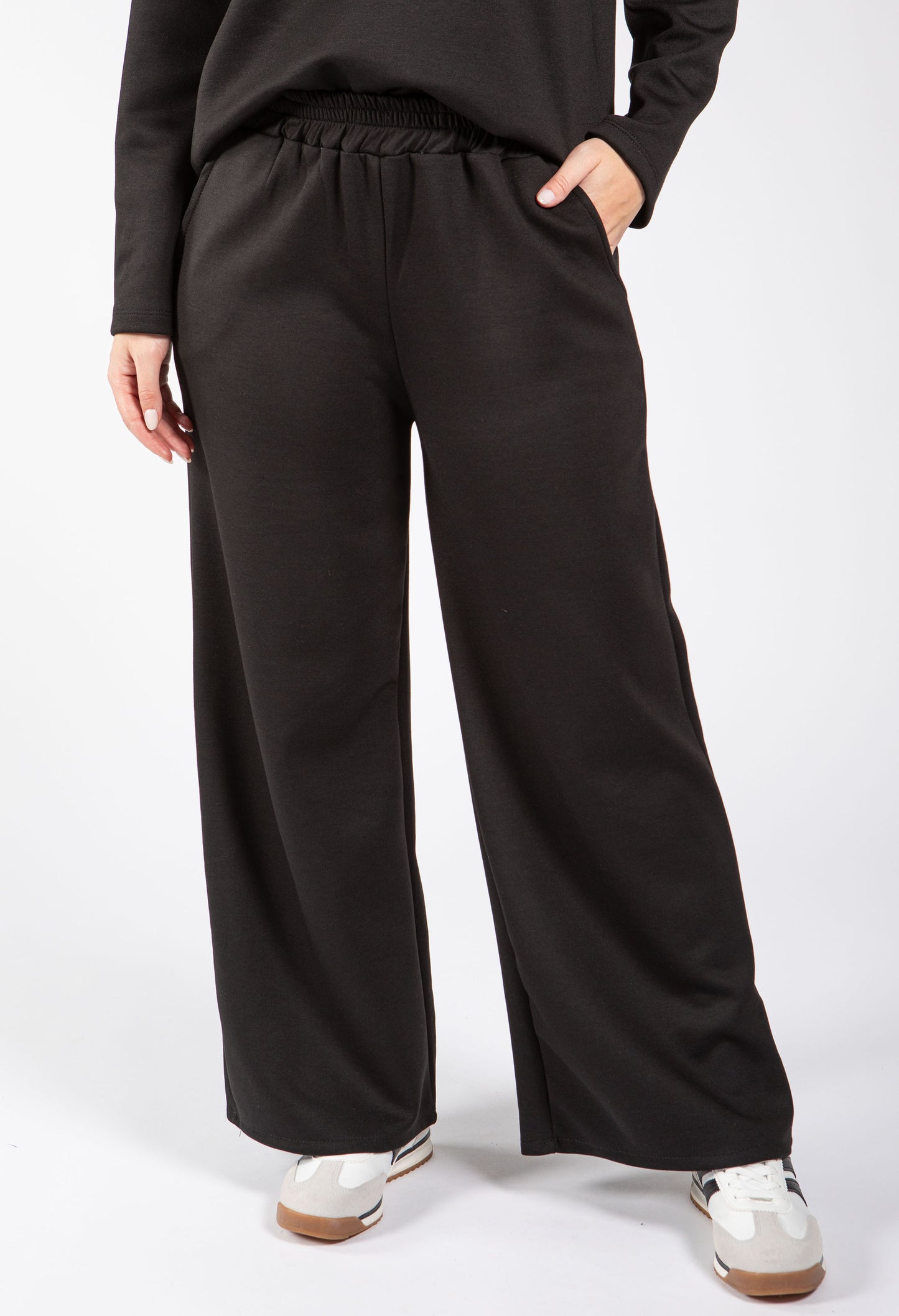 Person wearing black wide-leg pants on a white background
