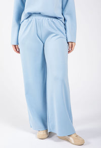 Person wearing a light blue outfit with pants and a sweater on a white background