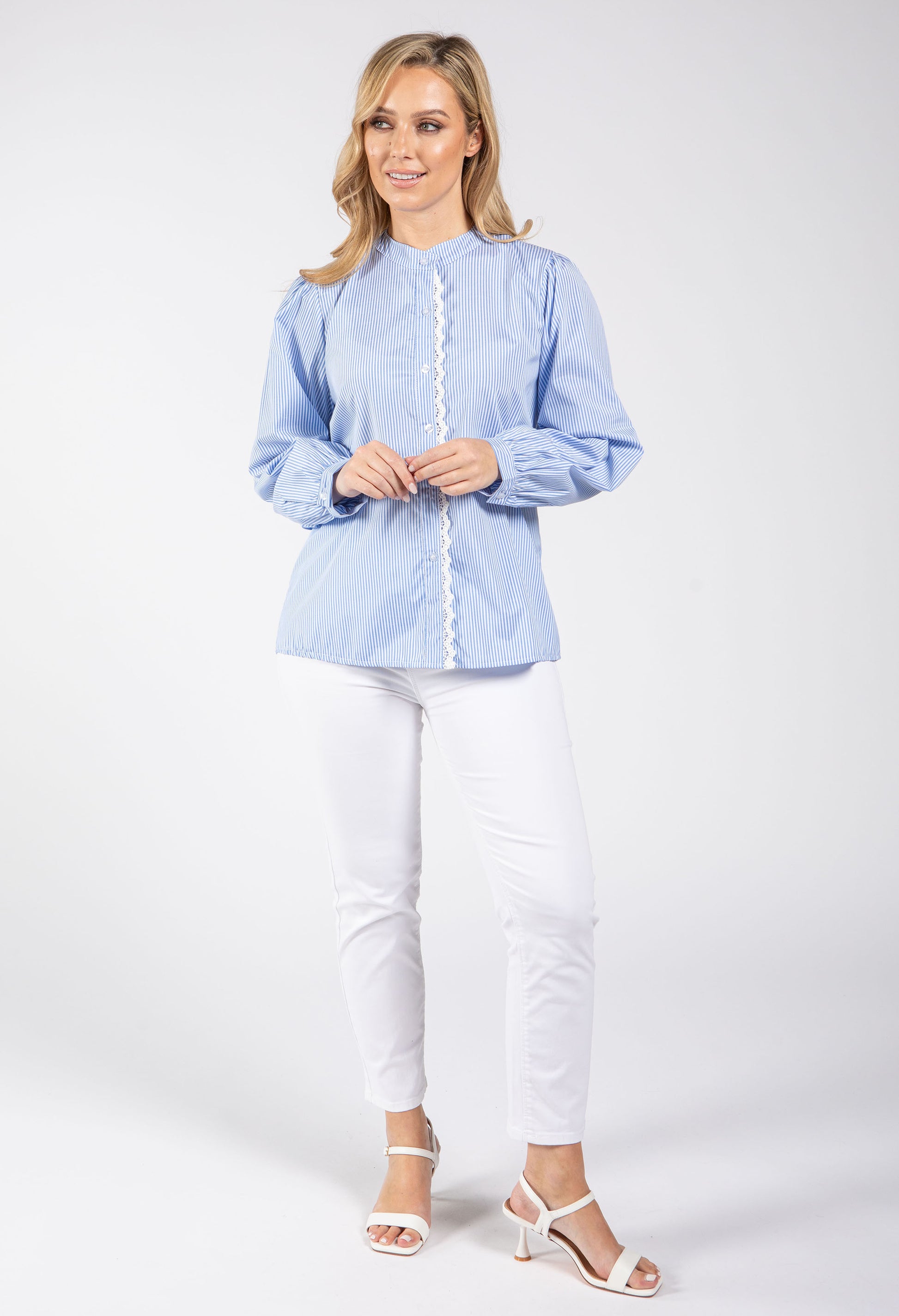 Woman wearing a light blue blouse and white pants on a white background