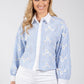 Woman wearing a blue and white floral embroidered shirt on a white background