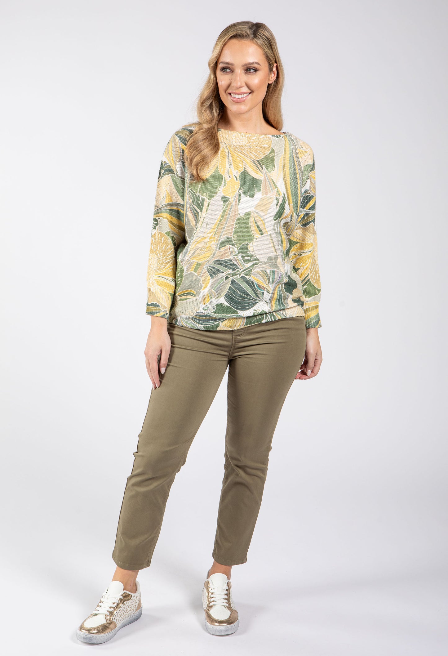 Woman wearing a floral patterned top and khaki pants on a white background