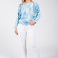 Woman wearing a blue tie-dye sweater and white pants on a white background