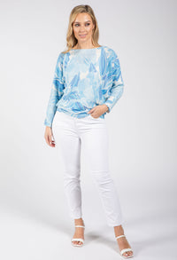 Woman wearing a blue tie-dye sweater and white pants on a white background