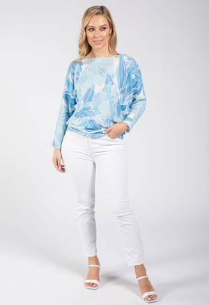 Woman wearing a blue tie-dye sweater and white pants on a white background