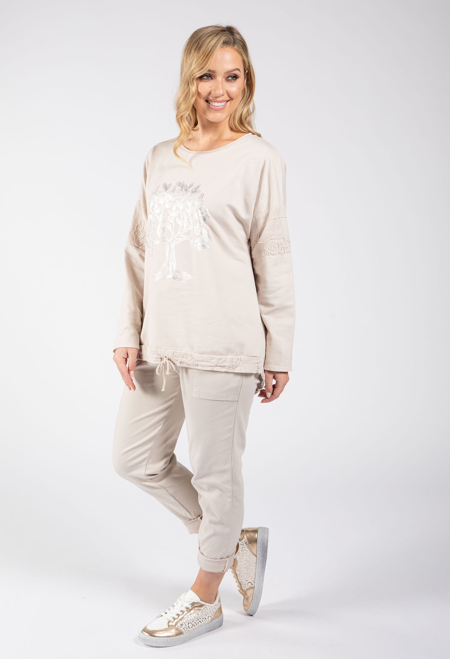 Woman wearing a beige sweatshirt and pants set on a white background