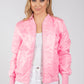 Woman wearing a pink bomber jacket on a white background