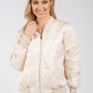Woman wearing a beige bomber jacket on a white background