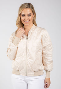 Woman wearing a beige bomber jacket on a white background