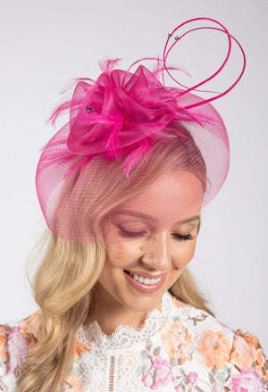Woman wearing a pink decorative headpiece against a white background
