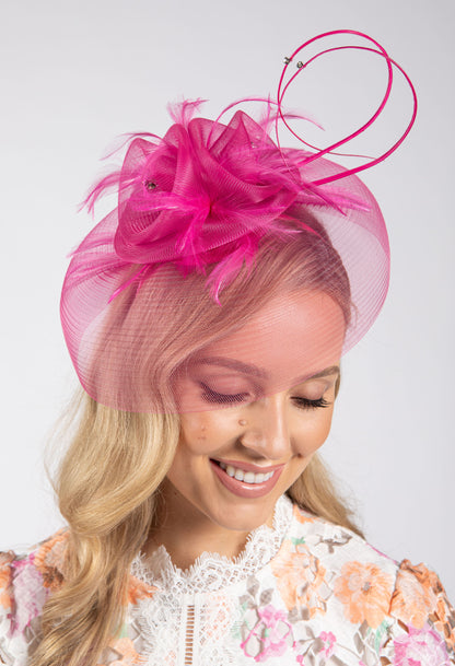 Woman wearing a pink decorative headpiece against a white background