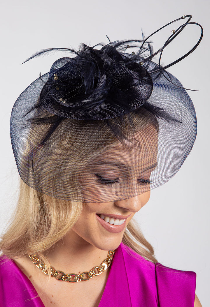 Woman wearing a black floral headpiece with a veil on a white background