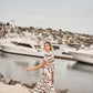 Woman walking by a marina with boats in the background