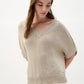 Woman wearing a beige knitted top against a white background