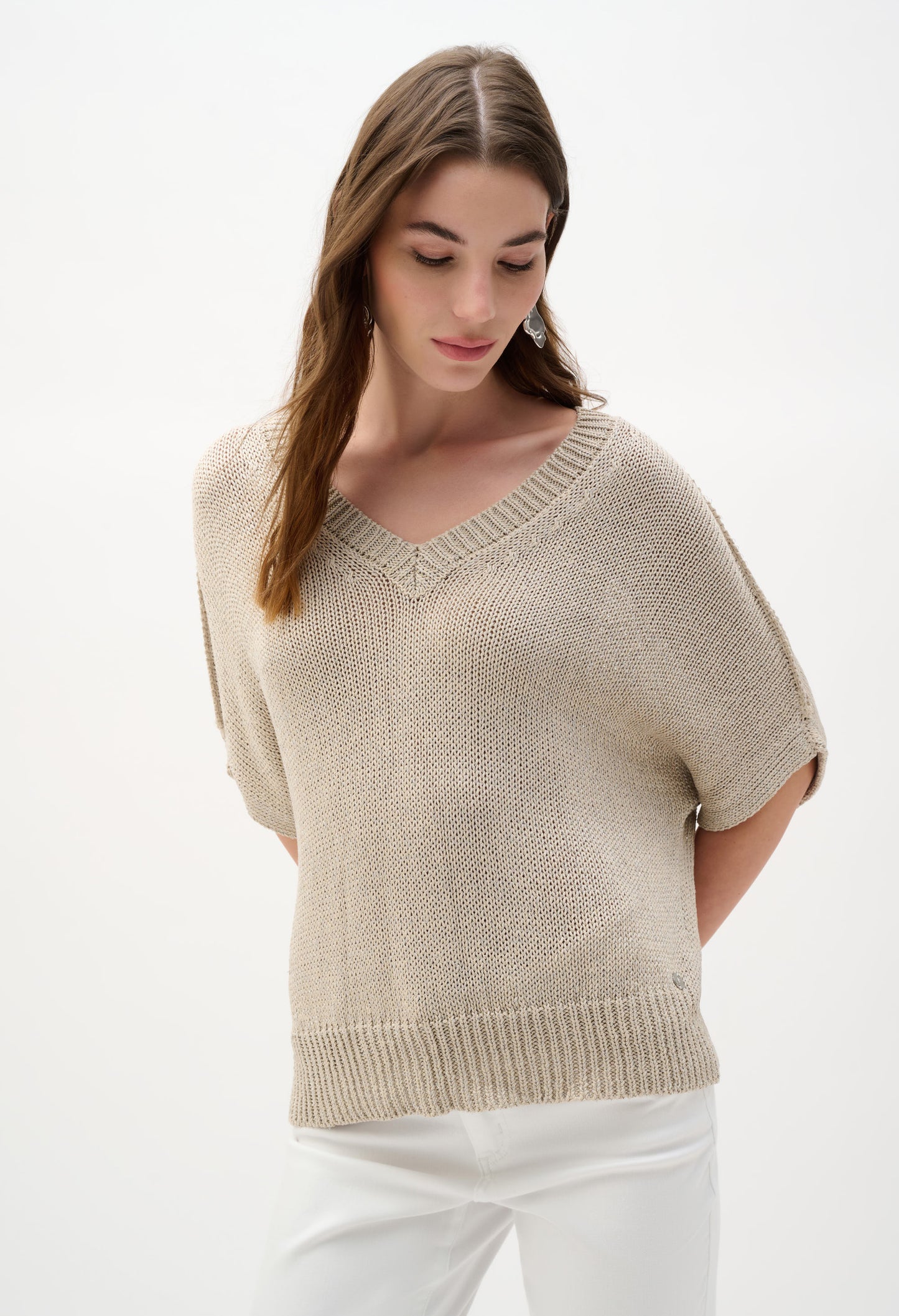 Woman wearing a beige knitted top against a white background