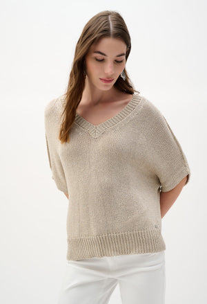 Woman wearing a beige knitted top against a white background