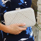 Person holding a silver beaded clutch with a floral dress in the background