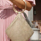 Gold beaded handbag held by a person wearing a pink dress outdoors.