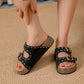 Person wearing black sandals with gold glittery soles on a textured surface
