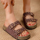 Brown sandals with glittery soles worn by a person on a textured surface