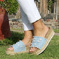 Person wearing light blue sandals with decorative straps on grass