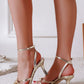 Gold high-heeled sandals worn by a person on a light background