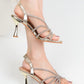 gold strappy high-heeled sandals on a white background