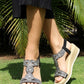 Person wearing embellished sandals on grass with a blurred background