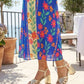 Person wearing a colorful floral dress and high-heeled sandals on a sunny day.