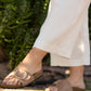Person wearing taupe sandals with a blurred green background