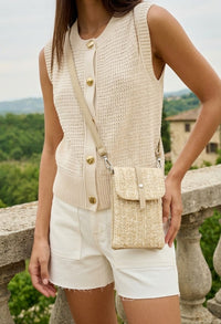 Person wearing a beige knitted vest with a matching crossbody bag, standing outdoors.