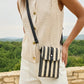 Person wearing a beige sleeveless top and shorts with a black and white striped crossbody bag, standing outdoors.