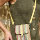 Person wearing a green knitted vest with a colorful striped bag over their shoulder.