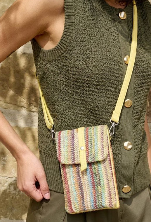 Person wearing a green knitted vest with a colorful striped bag over their shoulder.