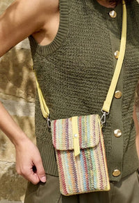 Person wearing a green knitted vest with a colorful striped bag over their shoulder.